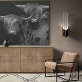 Schotse hooglander muurdecoratie in de vorm van een canvas schilderij hangt hier boven een dressoir of kast tegen een beige wand. Het maatwerk canvas is opgehangen met de canvas ophangbeugel en komt uit de zwart wit schilderij collectie