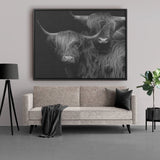 Canvas met lijst, fotoprint van twee Schotse hooglander zwart wit, prachtig ingelijst canvas schilderij. Het unieke schilderij hangt hier aan een witte muur boven een bank. De lijst die hier gebruikt is, is een zwarte houten baklijst van Kontoer design.