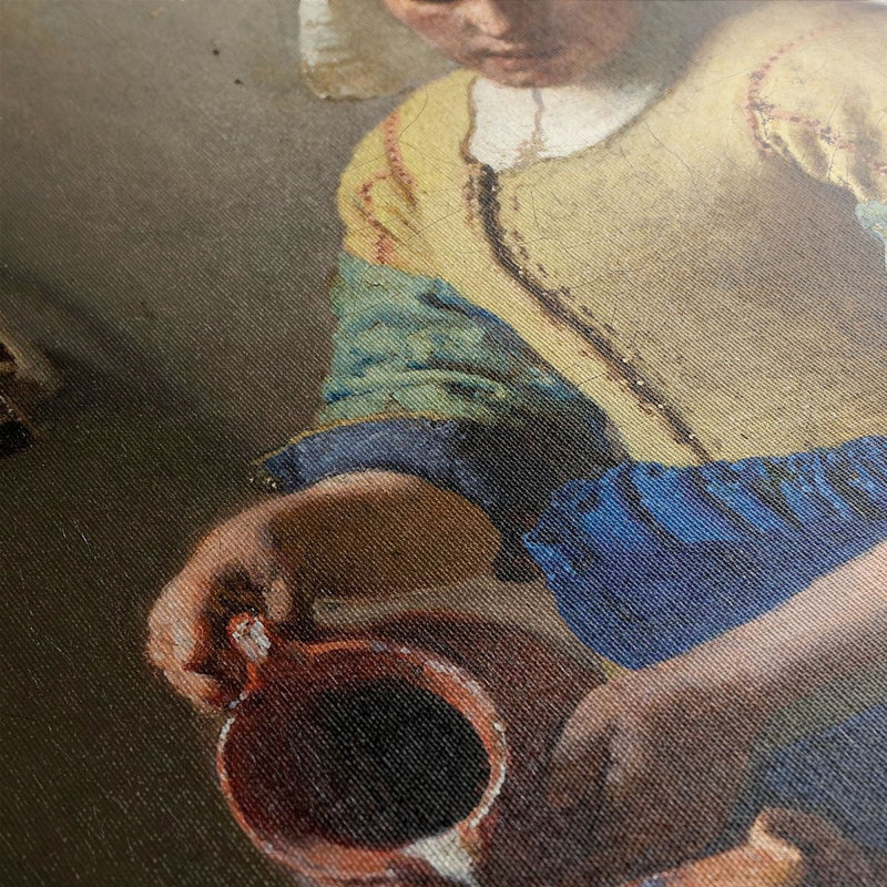 Melkmeisje schilderij van Johannes Vermeer van dichtbij. Je ziet hier details als penseelstreken en de structuur van het doek duidelijk terug. 
