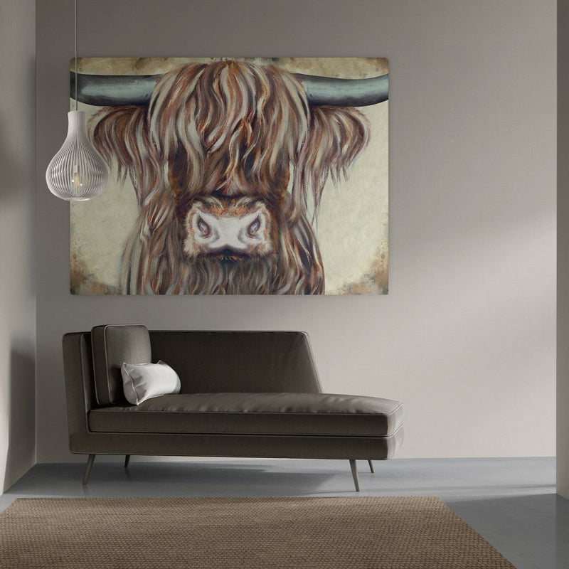 schilderij schotse hooglander op canvas boven een bank, dat is wat je hier ziet. 
