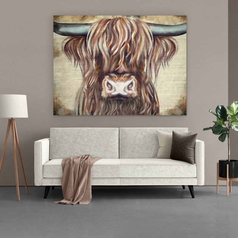 Het aluminium schilderij van een Schotse hooglander op grootformaat. De unieke muurdecoratie hangt hier boven een beige bank
