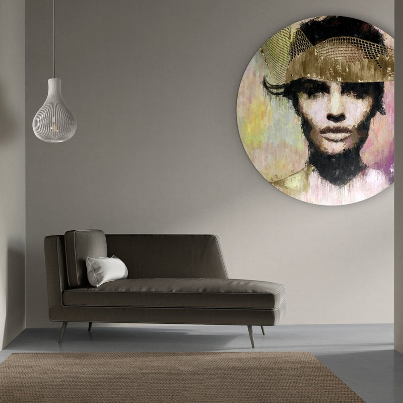 De wandcirkel toont een rond schilderij van een vrouw, deze vrouw is deels gehuld in een gouden net en de achtergrond is een explosie van kleuren en emoties