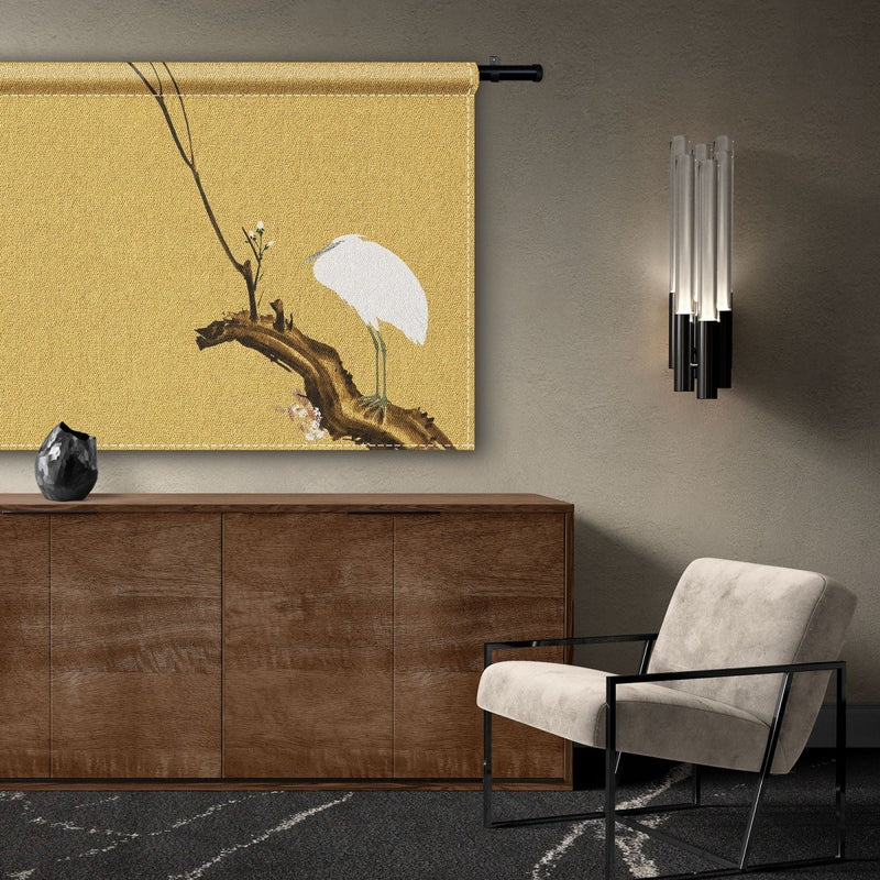 Dit is een breed wandjkleed met veel goud en een reiger in het wit. 