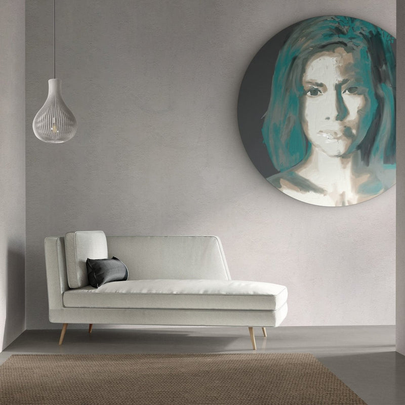 Hier hangt de wandcirkel groen boven een de bank. Het vrouwen portret is gemaakt van aluminium.